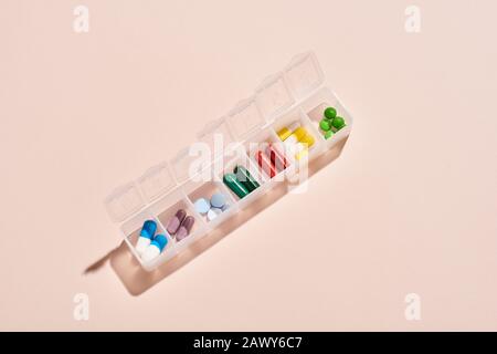 From above horizontal shot of portable plastic container for drugs with medicaments in it on pale pink background Stock Photo