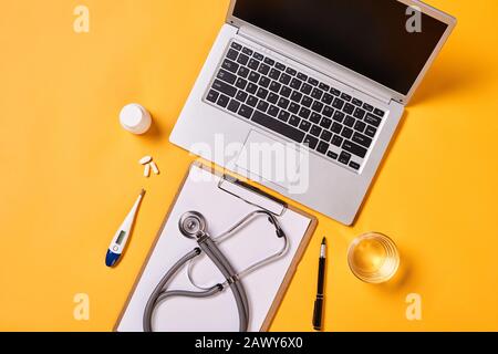 Horizontal from above flat lay shot of destop in modern doctor's office, yellow background Stock Photo