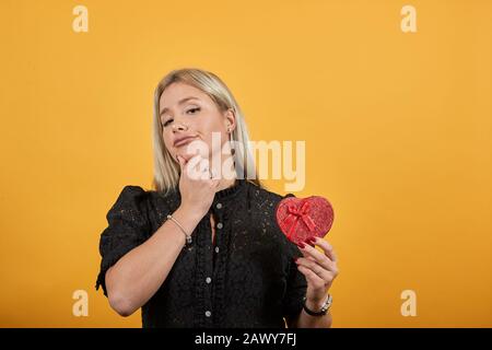girl in dress woman in love holds gift form of heart box thinks makes decisions Stock Photo