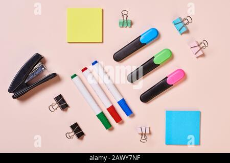 Highlighter pens, whiteboard markers, paper clips and sticker papers on pale pink background, flat lay shot Stock Photo