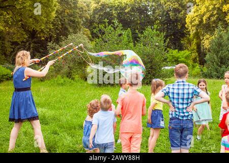 Young woman entertains children with soap bubbles Stock Photo