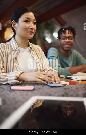 Multi-ethnic group of three business people working on project while sitting at table in cafe during meeting,digital tablet in foreground Stock Photo