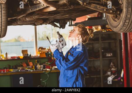 Young female mechanic works under the car Stock Photo