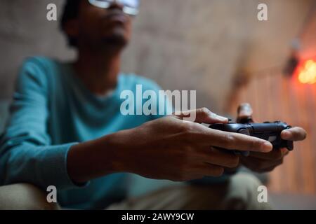 Close up of contemporary African-American man holding gamepad controller while playing videogames Stock Photo