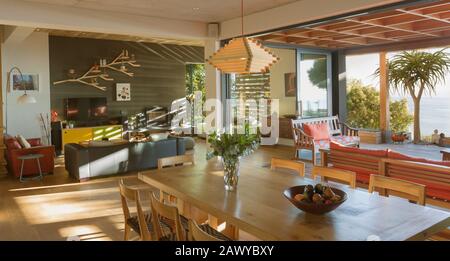 Sunny modern, luxury home showcase interior dining room open to patio Stock Photo