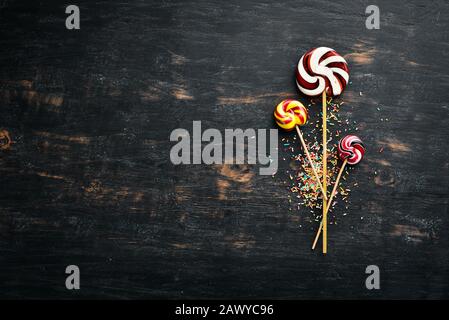 Caramel candies and lollipops. Colored candies. On a black background. Top view. free copying space. Stock Photo