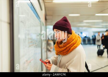 Young woman with smart phone checking subway map Stock Photo