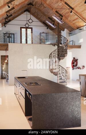 Home showcase interior kitchen with vaulted ceiling and spiral staircase loft Stock Photo