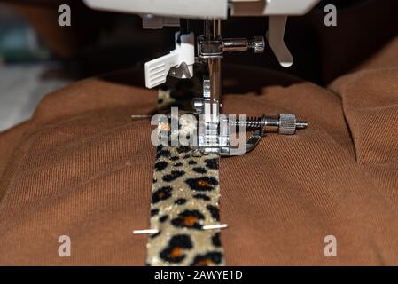 Close-up view of working sewing machine sewing brown fabric Stock Photo