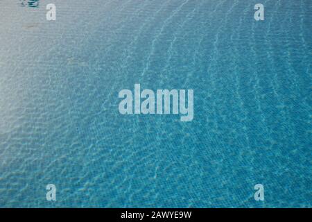 Reflections in blue swimming pool. Blue mosaic tiled pool with a gentle ripple. Stock Photo