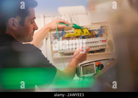Electrician testing fuse box with voltmeter Stock Photo