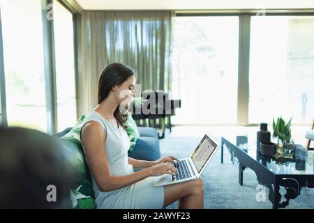 Businesswoman working from home, using laptop on sofa Stock Photo