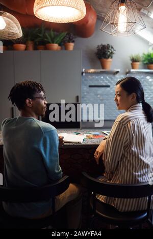 Back view portrait of two contemporary designers discussing color swatches in kitchen interior, copy space Stock Photo