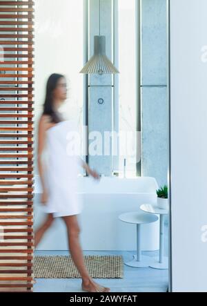 Woman wrapped in a towel walking in luxury, modern bathroom Stock Photo