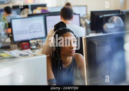 Focused businesswoman with headphones working at computer in office Stock Photo