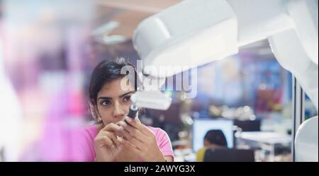 Focused female engineer with screwdriver fixing robotic arm Stock Photo