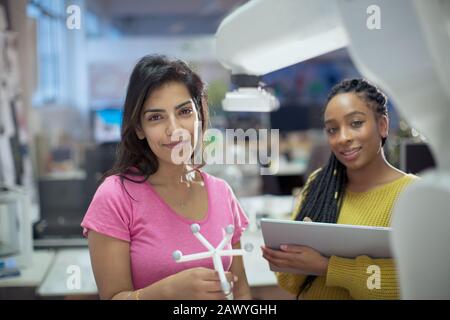 Portrait confident female engineers with prototype and robotic arm in office Stock Photo