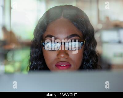 Close up focused young woman in eyeglasses working at computer Stock Photo