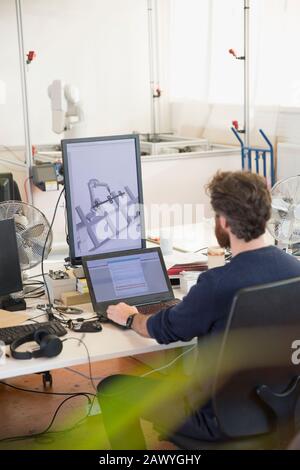 Male engineer programming robotics, working at laptop in office Stock Photo