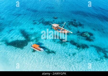 Aerial view of the fishing boats in clear blue sea at sunset