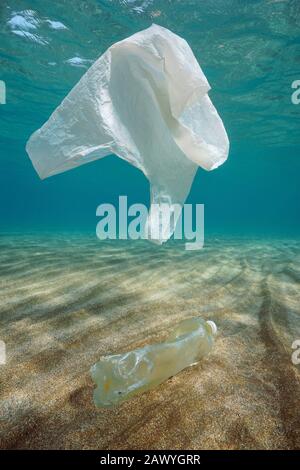 Plastic pollution in sea underwater, a plastic bag drifts and a bottle on a sandy seabed in the Mediterranean, France Stock Photo