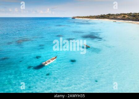 Aerial view of the fishing boat in transparent blue water at sunset in ...