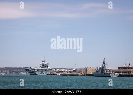 HMS Mersey (P283) the River-class offshore patrol vessel is dwarfed by the aircraft carrier HMS Queen Elizabeth in the background. Stock Photo