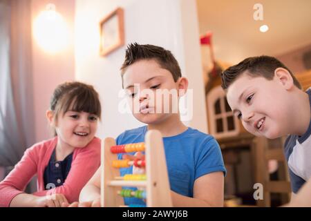Boy with Down Syndrome and siblings playing with toy Stock Photo