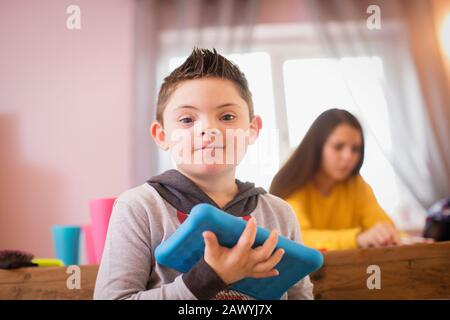Portrait smiling boy with Down Syndrome using digital tablet Stock Photo