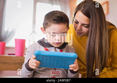 Girl watching brother with Down Syndrome using digital tablet Stock Photo