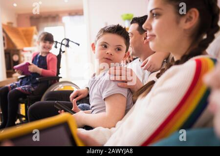 Boy with Down Syndrome watching TV with family Stock Photo