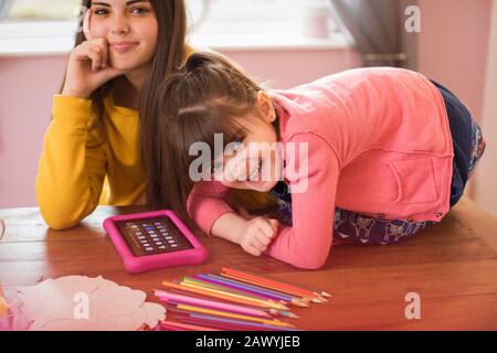 Portrait happy sisters using digital tablet on table Stock Photo