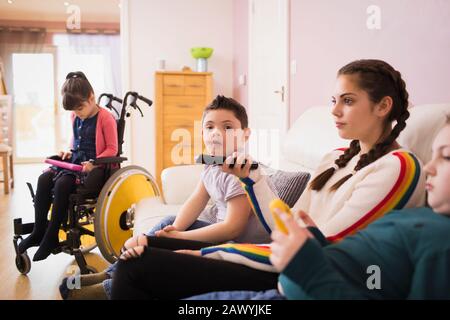 Portrait boy with Down Syndrome watching TV with family on sofa Stock Photo