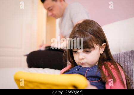 Focused girl using digital tablet on sofa Stock Photo