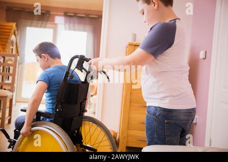 Boy pushing brother in wheelchair Stock Photo