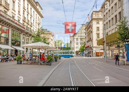 Zurich, Switzerland - June 10, 2017: Shopping promenade called Bahnhofstrasse, inner city of Zurich. Cafe with people sitting in front, tram / train i Stock Photo