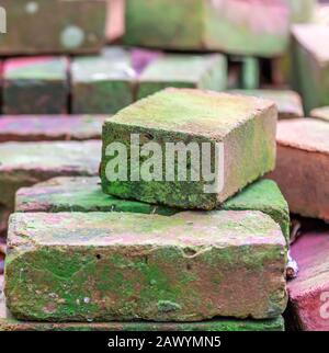 Stack of crudely stacked old bricks that have green moss Stock Photo