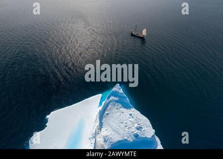 Drone point of view ship sailing past iceberg on sunny ocean Greenland Stock Photo