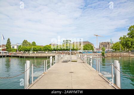 Shipping pier at Burkliplatz, where excursion ships starts for boat trips over Lake Zurich and river Limmat. View towards inner city of Zuerich. Stock Photo