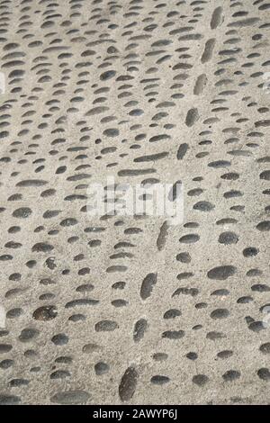 A street with small black stones set in cement. Cobbled road surface. Stock Photo