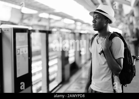 Young African tourist man thinking while waiting for the train at skytrain station Stock Photo