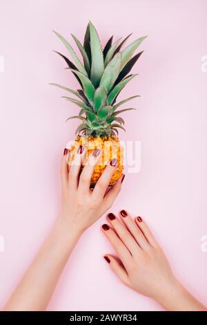 Hands with pineapple on stylish pink background. Stock Photo