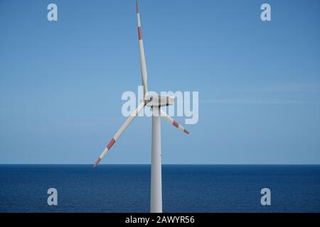 Small power generating wind turbine. Sea and horizon behind. Stock Photo