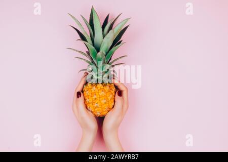 Hands with pineapple on stylish pink background. Stock Photo