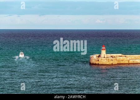 Lighthouse in the calm Mediterranean sea waters in sunny day with blue sky Stock Photo
