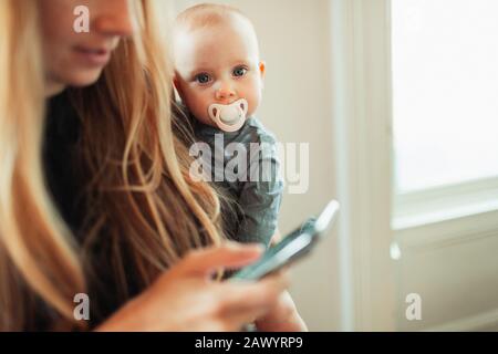Portrait mother holding baby daughter with pacifier Stock Photo