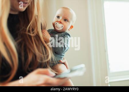 Cute baby girl with pacifier in mother arms Stock Photo
