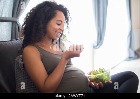 Happy young pregnant woman eating salad Stock Photo