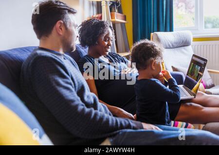 Pregnant family using laptop on sofa Stock Photo