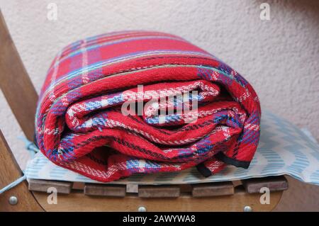 Closeup shot of a folded red blanket on a wooden chair Stock Photo